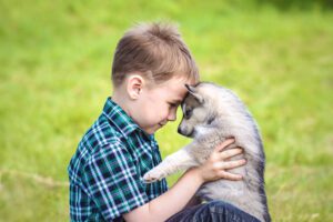 A child and a puppy cuddle