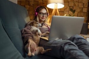 A girl with a dog watching a movie on a laptop with headphones. Pets and pet friends for people.