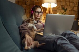 A girl with a dog watching a movie on a laptop with headphones. Pets and pet friends for people.